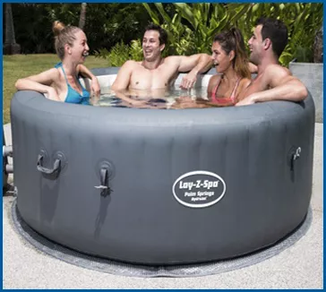 Four people relaxing in a grey Lay-Z-Spa inflatable hot tub