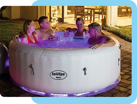 Four people relaxing in an illuminated inflatable hot tub at night