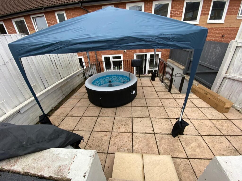 Inflatable hot tub installed on a flat paved patio beneath a gazebo